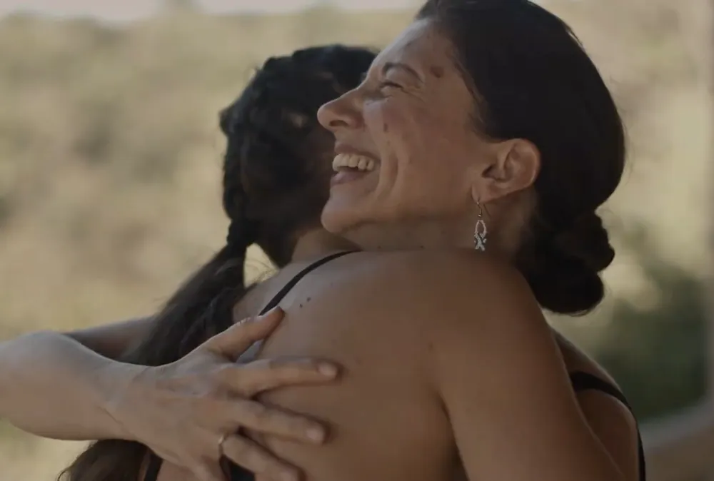 Two women laughing as they hug each other
