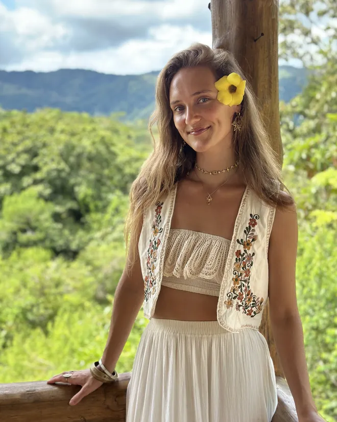 Maisie on a balcony above the rainforest, a yellow flower in her hair