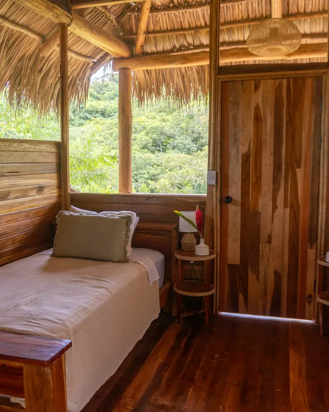 Inside a cabin, two beds and a window onto the trees