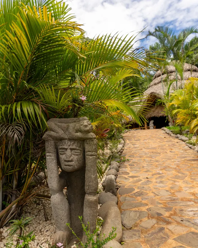 A stone statue beside the path to the Maloca