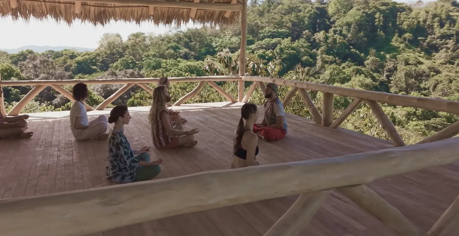 A group meditating in the yoga shala, surrounded by rainforest