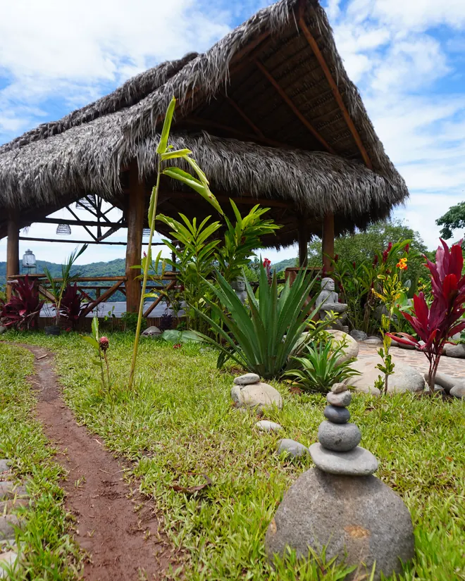 The yoga shala from the side, a stone cairn in the grass